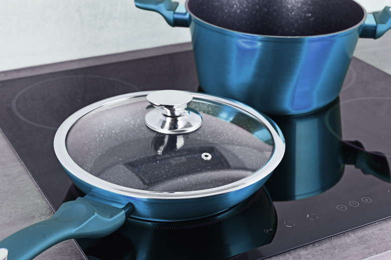 Frying pan and steel pot on modern induction cooktop