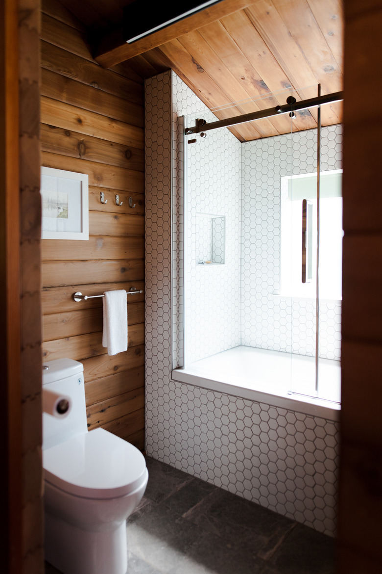 bathroom view with shower/tub combo, toilet and wood-paneled walls and ceilings