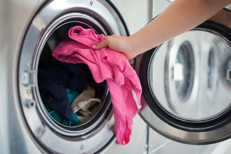 Woman putting shirt into washing machine