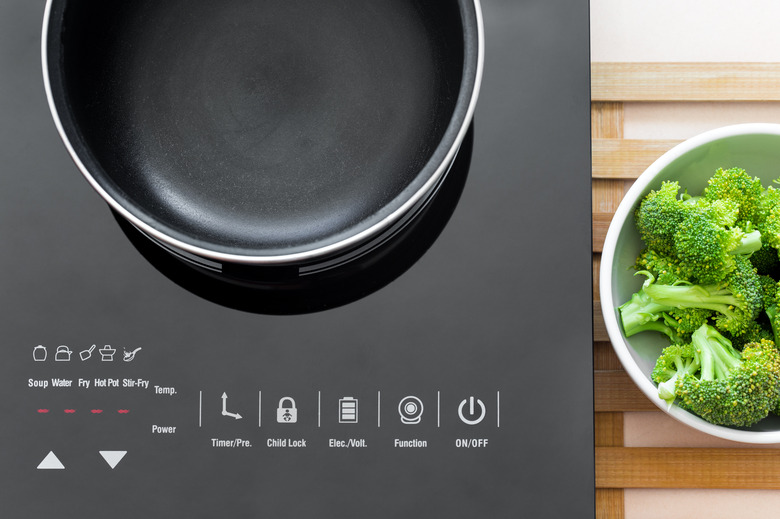 Boiling water at pan on Induction stove top panel for cooking broccoli