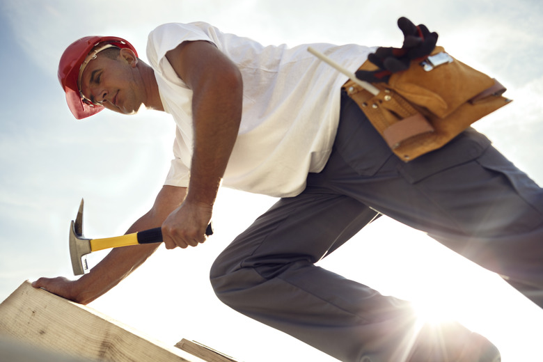 Construction roofer nailing wood board with hammer