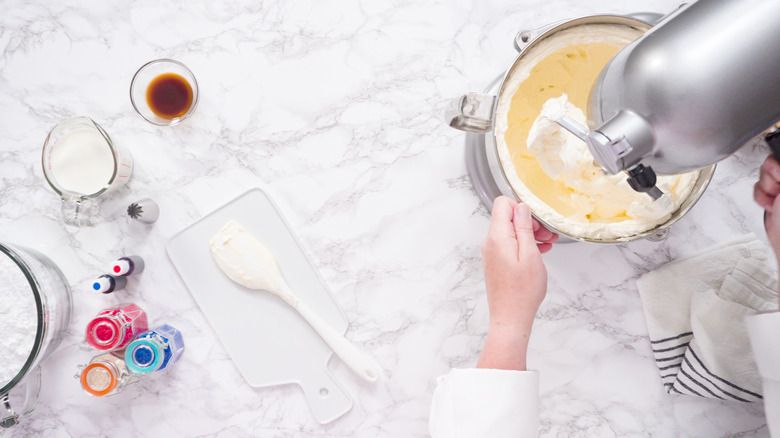 Mixing ingredients in standing kitchen mixer to make buttercream frosting.