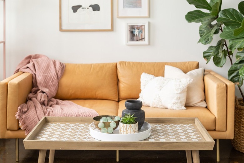 Wood coffee table with a white stencil star pattern, white tray with accent pottery, mustard sofa with white pillows