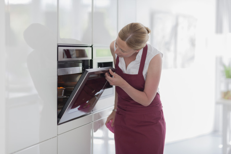 Woman using oven in kitchen