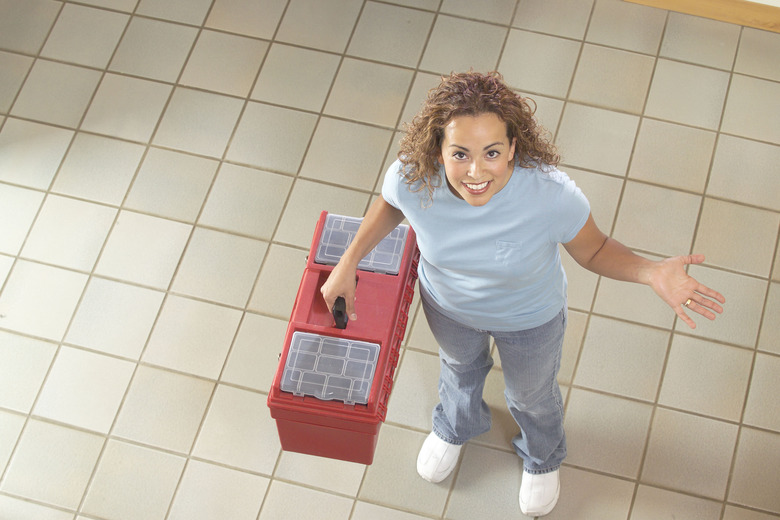 Woman Standing on Tile Floor Holding Toolbox