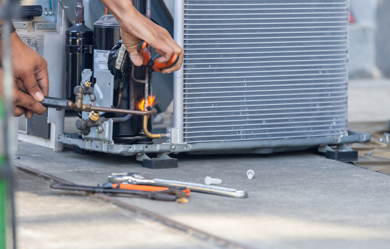 Close up of Air Conditioning Repair team use fuel gases and oxygen to weld or cut metals, Oxy-fuel welding and oxy-fuel cutting processes, repairman on the floor fixing air conditioning system