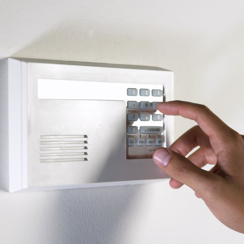 Hand of a woman pressing a key on a security alarm keypad