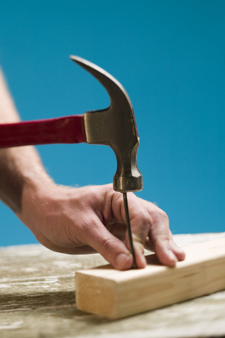 Person hammering nail into wood