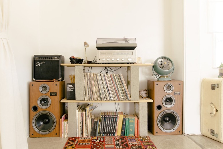 amplifiers and speakers surround shelves made of wood and cinderblock holding vinyl records