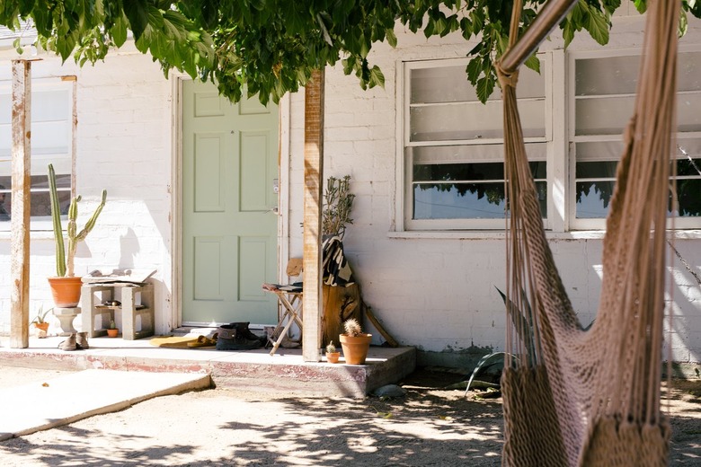 the front door is painted green and surrounded by cacti