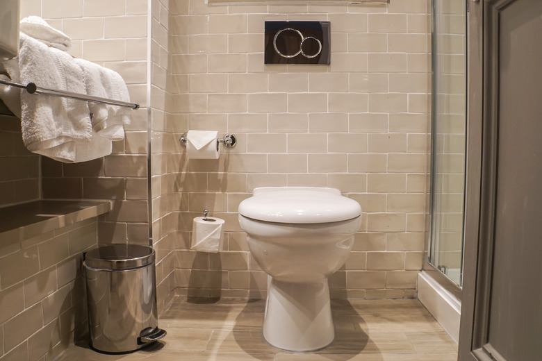 toilet bowl, tissue roll and white towels with luxury decorative in bathroom