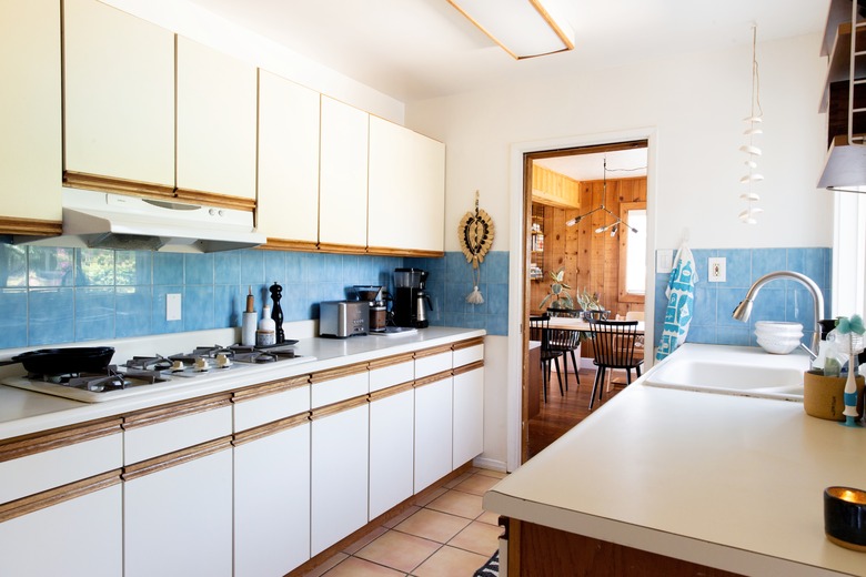 galley kitchen with blue tile backsplash and white cabinetry