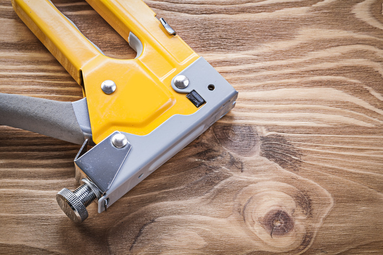 Staple gun on wooden board directly above construction concept