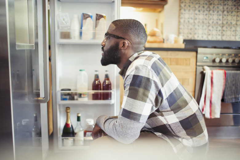 Hungry man peering into refrigerator in kitchen