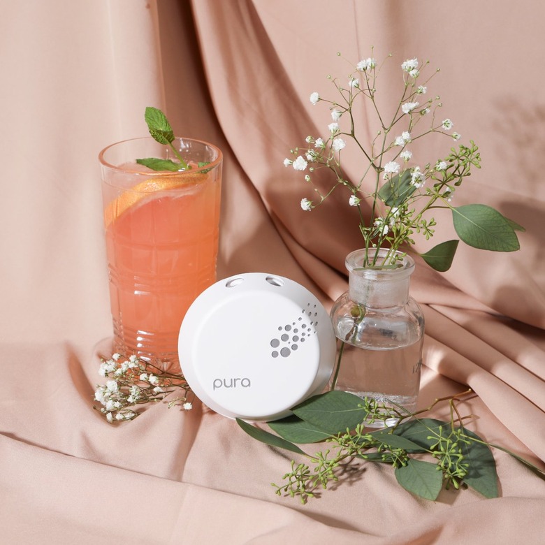 white plug-in diffuser with glass of juice and vase with flowers