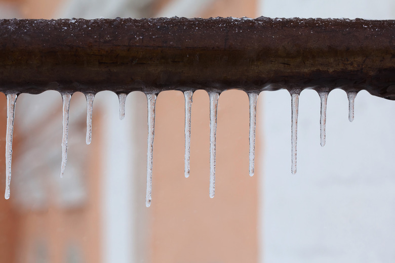 Icicles hanging from a brown pipe. Frozen water and metal surface, winter time concept. selective focus shallow depth of field photo