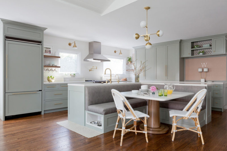 kitchen island with bench seating with green cabinets and bistro chairs