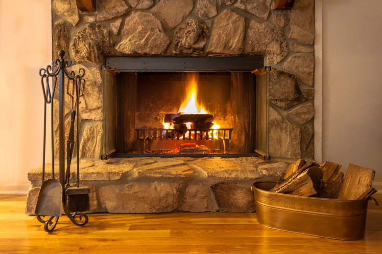 Stone fireplace with logs burning in a residential home.