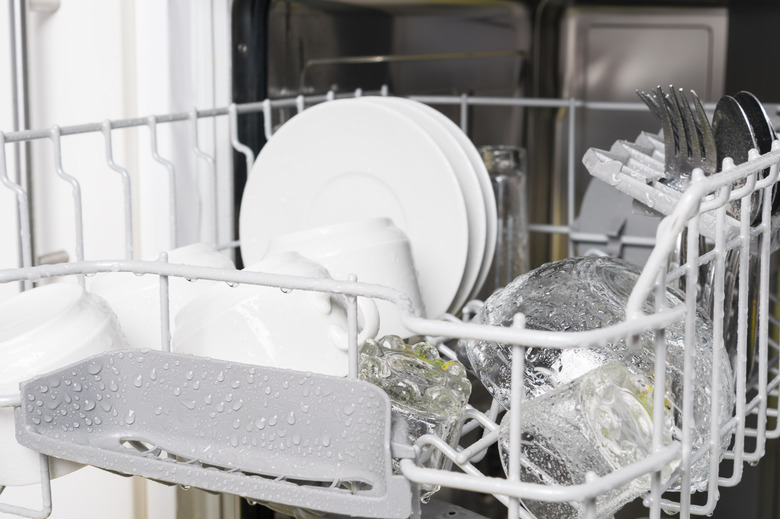 wet clean white dishes and cutlery are in the dishwasher