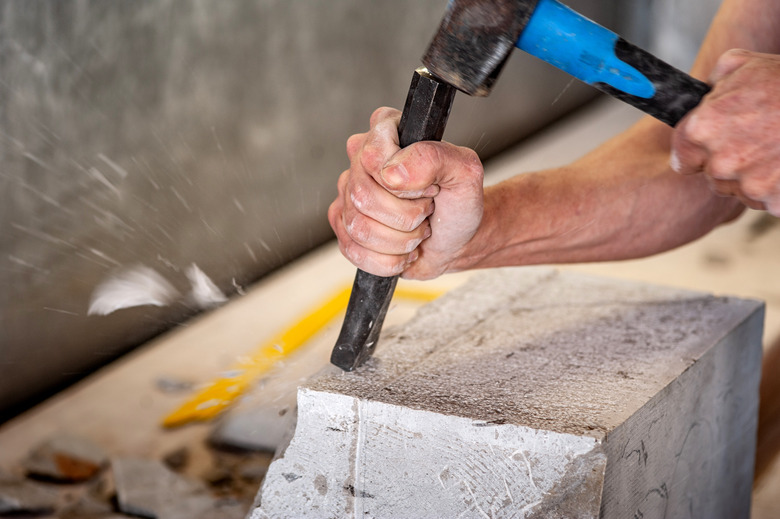 Closeup of mason working with hammer and chisel.