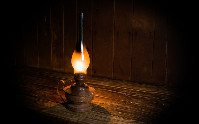 Antique burning paraffin lamp near on the wooden table.