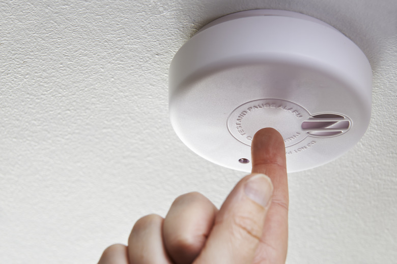 Close Up Of Hand Testing Domestic Smoke Alarm