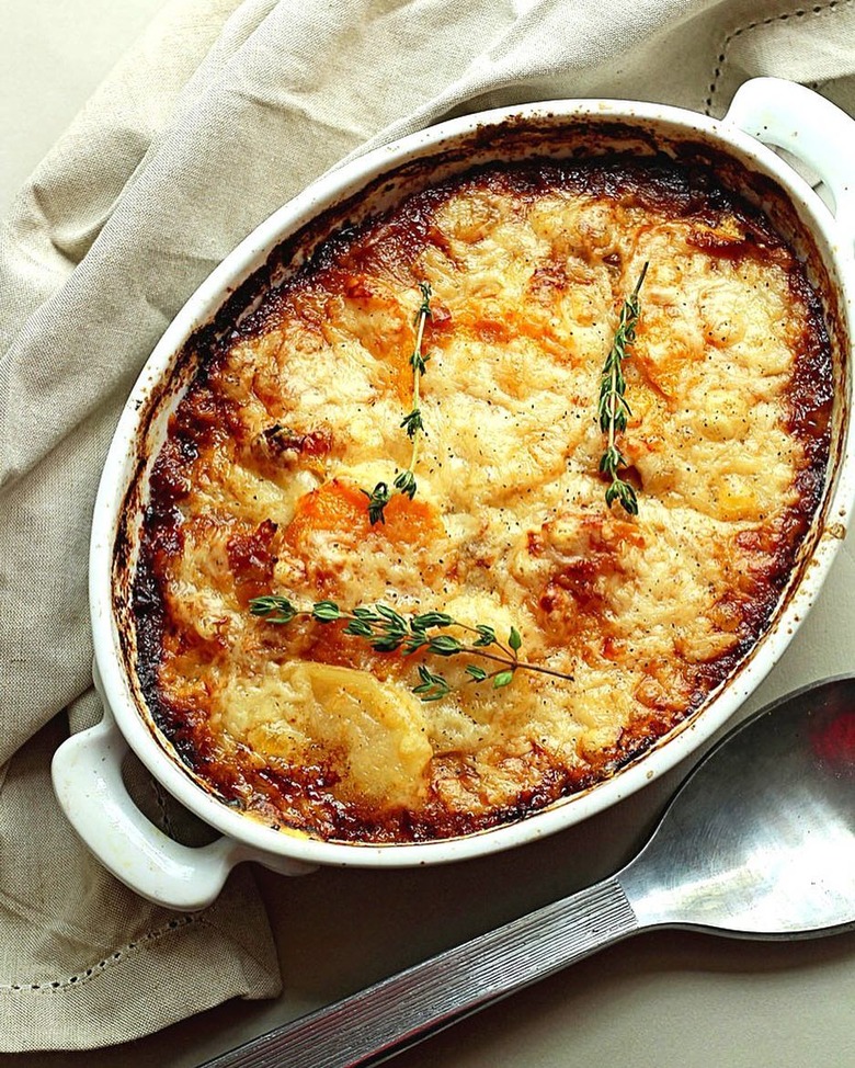 Grandbaby Cakes Potato and Squash Gratin in casserole dish with herbs on top