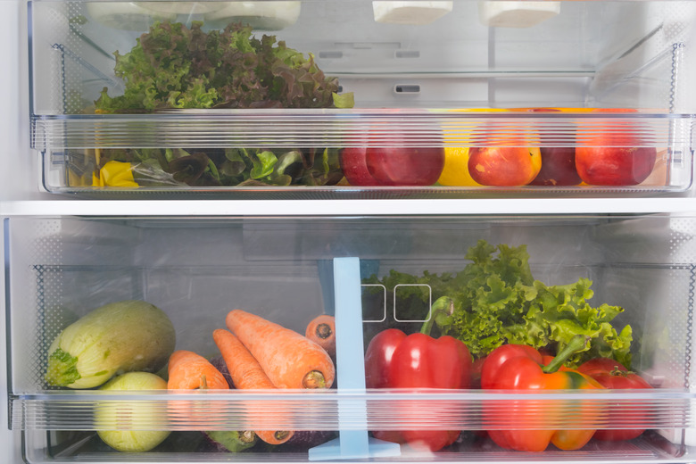 Produce drawers in refrigerator with a variety of vegetables and fruits.