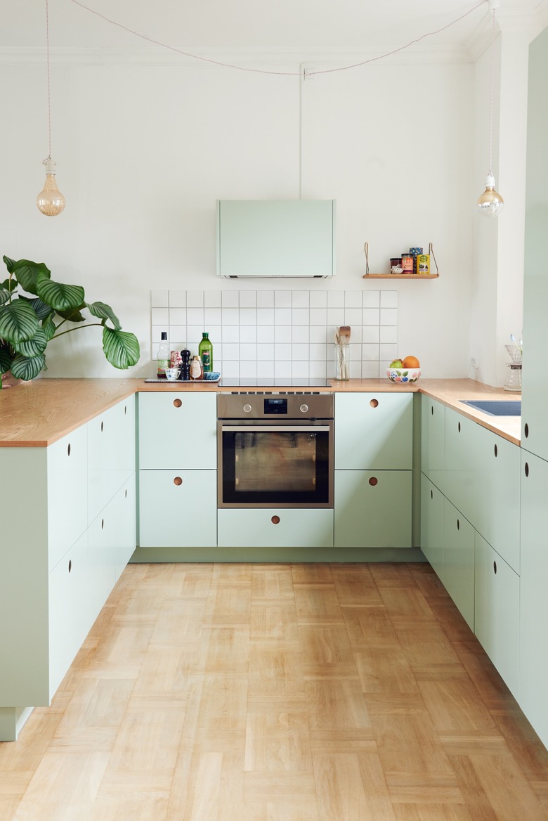 Scandinavian mint green kitchen with wood countertops and wood flooring