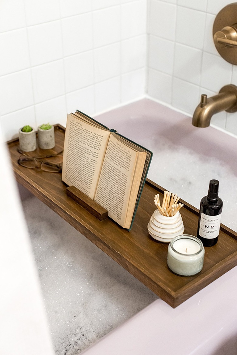 Wood bath tray with reading glasses, book, plants over bathtub