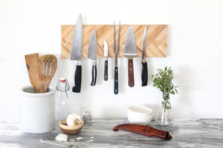 a knife holder made from magnets behind a layer of herringbone paint sticks mounted on a kitchen wall