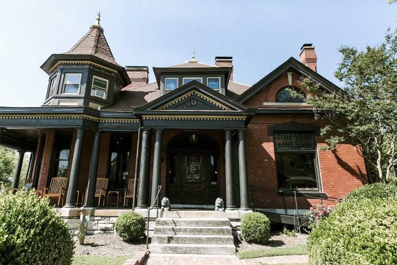 a building with a brick exterior, gables, a turret room, and wooden pillars