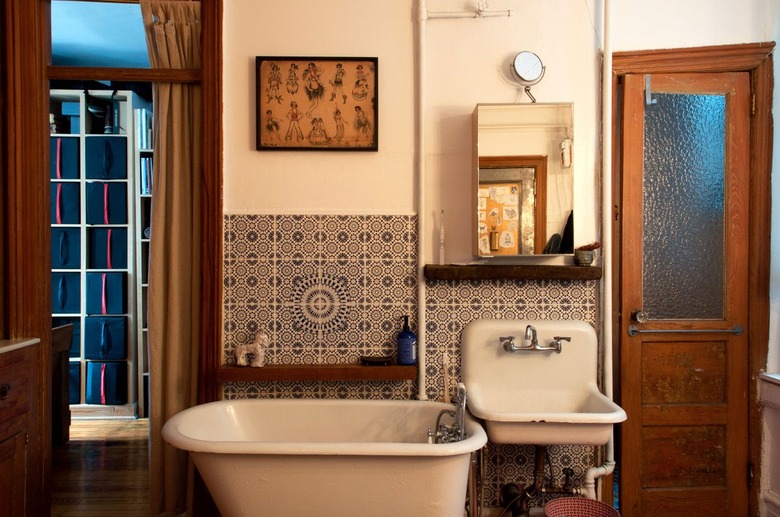 Rustic, old-fashioned style bathroom with white tub and sink, curtain, tiled walls, and wood door