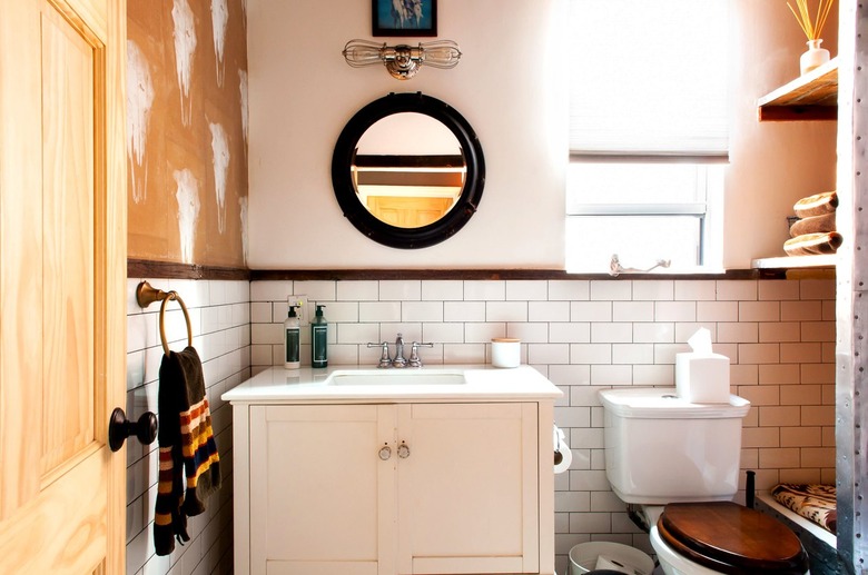 a bathroom with subway tile, a rustic wooden vanity and a cow-skull stencil patter on a wall