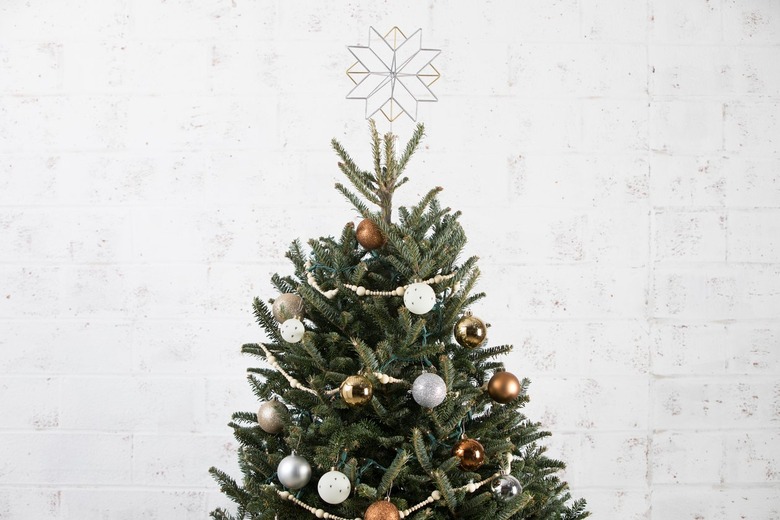 the top of a christmas tree decorated with ornaments, strings of beads, and a star