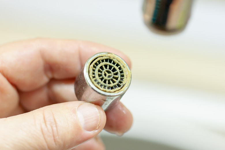 repair aerator faucet. replacing an old mixer. A person holds in his hand an old dirty limestone aerator.