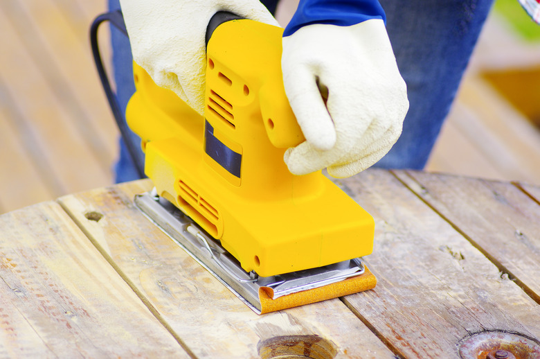 eyellow electric sander over a wood table