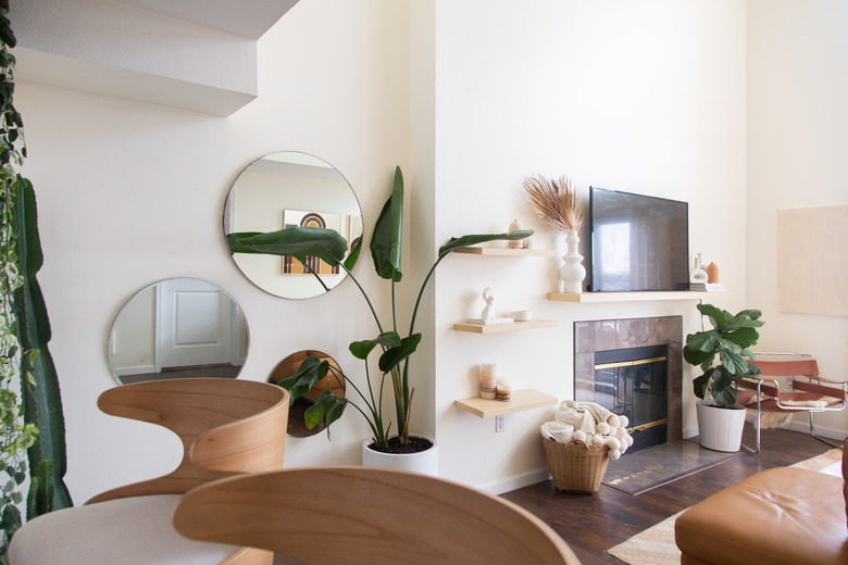 Living room with fireplace, plants, neutral colors, mirrors on wall