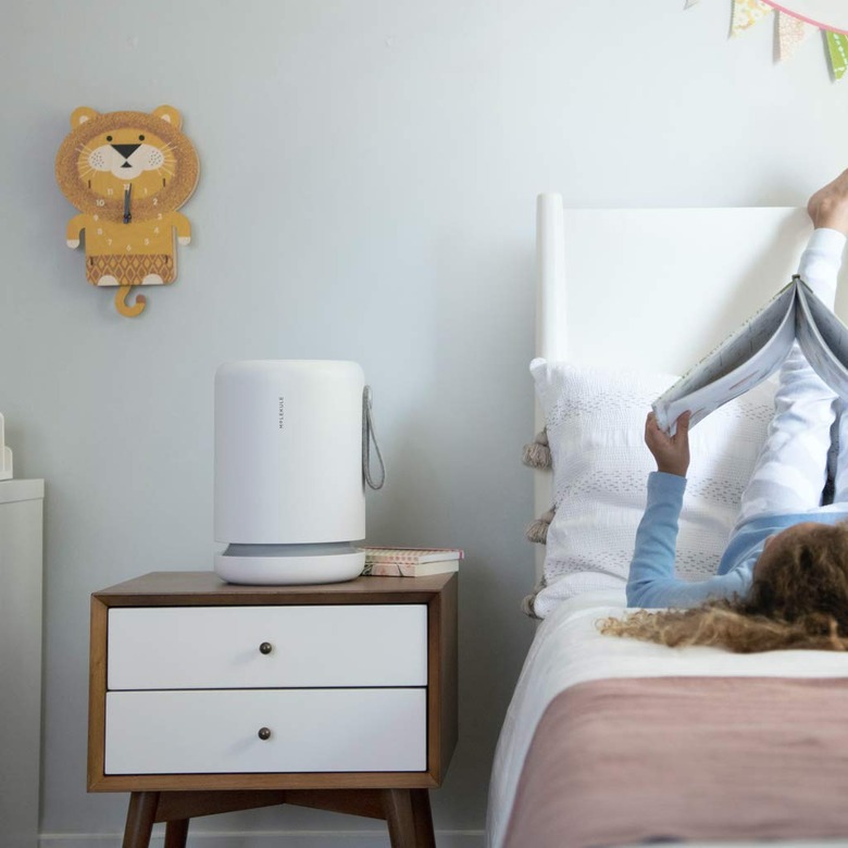 White cylindrical air purifier on bedside table