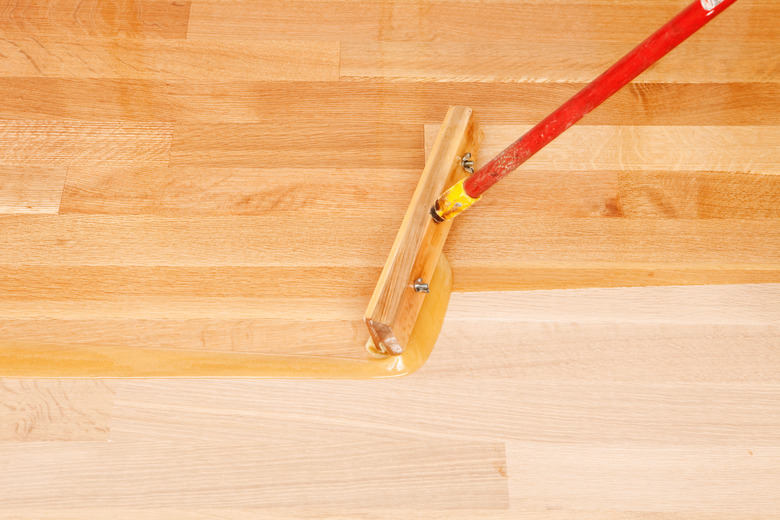 Squeegee Style Brush Applying Clear Polyurethane to Hardwood Floor