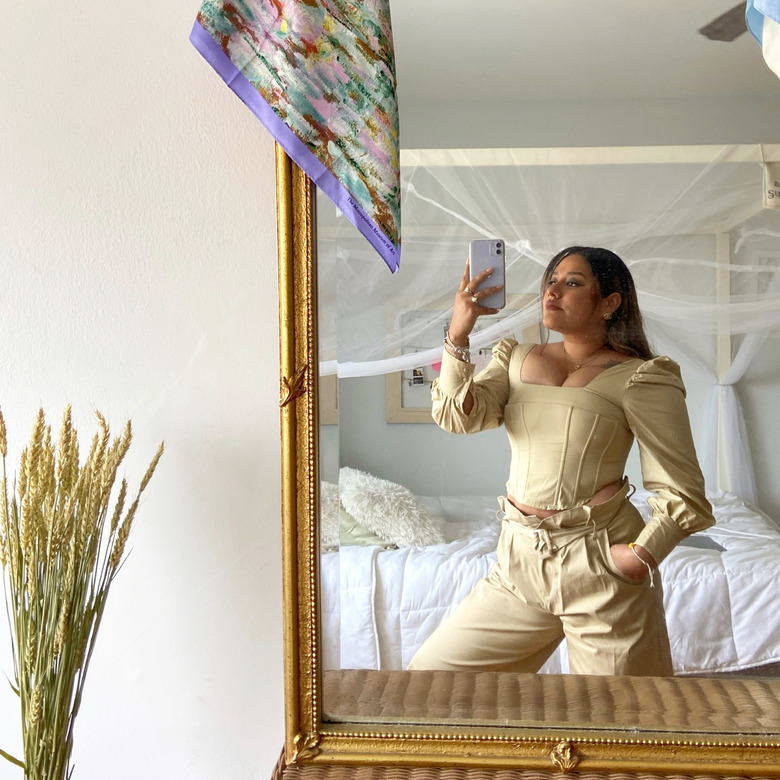 person standing in front of mirror with bed in background