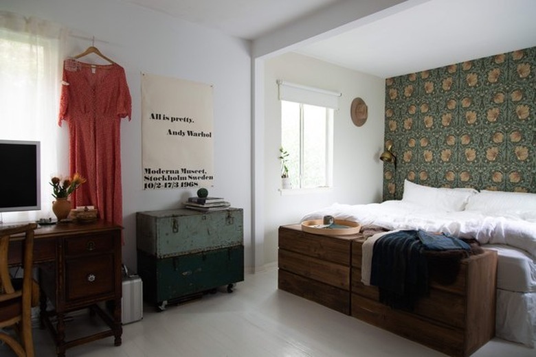 bedroom space with hanging dress and green wallpaper