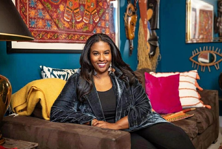 Seana Freeman on brown couch with colorful pillows and tribal wall hangings