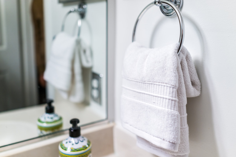 Staging modern bathroom with one decorated towel hanging on rack by sink in model home, apartment or house