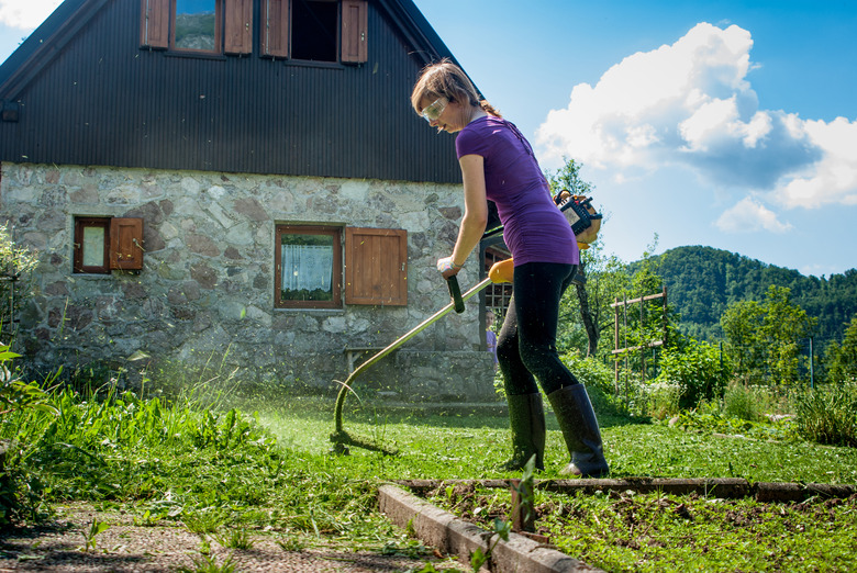 Woman Cutting The Lawn With Weed Trimmer