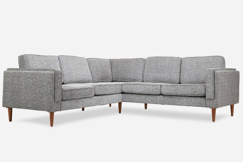 A grey fabric corner sectional from Albany Park with walnut legs