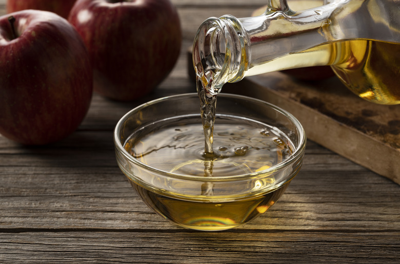 Apple vinegar in a glass container against a wooden background