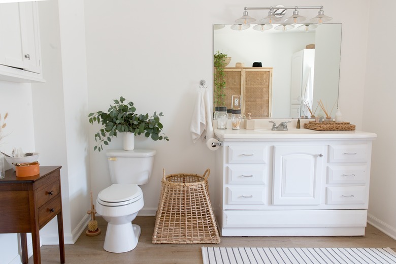 view of single-sink bathroom vanity, bathroom mirror, toilet and decorative baskets