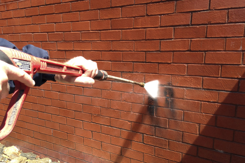 Pressure washing brick wall.