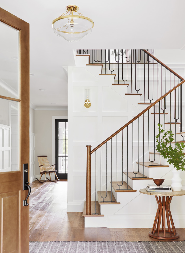 Traditional entryway table with vintage visuals alongside black and white staircase